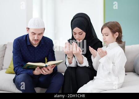 Muslimische Familie liest den Koran und betet zu Hause Stockfoto