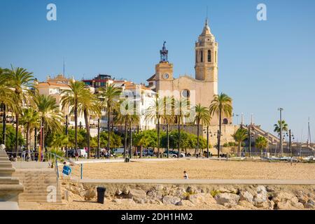 Blick auf den Strand von Sitges mit der Kirche Sant Bartolome und Santa Tecla im Hintergrund. Katalonien, Spanien Stockfoto