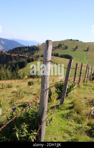 Nahaufnahme auf einem Stacheldrahtzaun auf einer Wiese In den Bergen Stockfoto