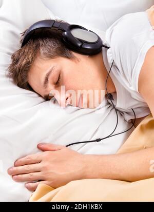 Junger Mann schlafen in Kopfhörer im Bett im Zu Hause Stockfoto