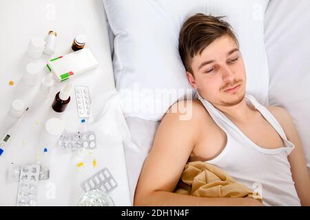 Trauriger und kranker junger Mann im Bett im Zu Hause Stockfoto