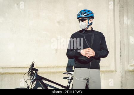 Radfahrer in Gesichtsmaske durch Smog in der Stadt. Fahrrad Kurier eine Lieferung. Mann mit Covid 19 Coronavirus Maske. Radfahrer in Stockfoto