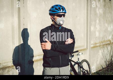 Radfahrer in Gesichtsmaske durch Smog in der Stadt. Fahrrad Kurier eine Lieferung. Mann mit Covid 19 Coronavirus Maske. Radfahrer in Stockfoto