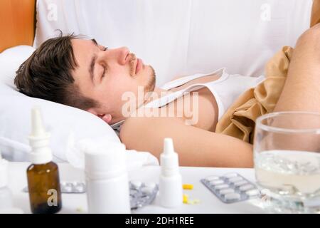 Trauriger und kranker junger Mann im Bett im Zu Hause Stockfoto