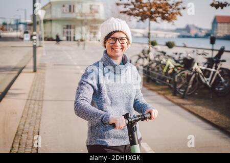 Junge Frau, die einen Elektroroller auf Radweg in kopenhagen, modernes Mädchen, neue Generation, Elektrotransport in der Stadt, ecol Stockfoto