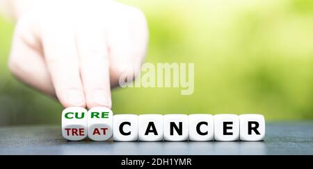 Die Hand dreht Würfel und ändert den Ausdruck „Treat Cancer“ in „Cure Cancer“. Stockfoto