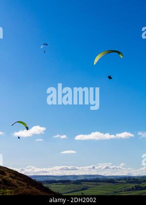 Gleitschirme fliegen in einem klaren blauen Himmel über Bradwell Edge Im Peak District National Park Derbyshire England Stockfoto