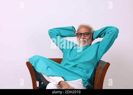 Älterer indischer Mann, der sich entspannt oder auf einem Stuhl sitzt. Stockfoto