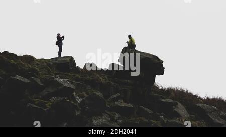 Menschen, die für ein Foto im Freien mit einem Hund auf dem Land posieren, Pancake Stone, Ilkley Moor, West Yorkshire, England, Großbritannien Stockfoto