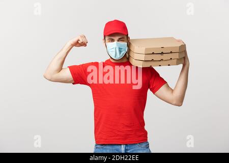 Lieferkonzept - Portrait des Starken, gutaussehenden Lieferers, der seine Muskel- und Pizza-Box-Pakete hält. Isoliert auf Grau Stockfoto