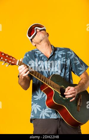Portrait eines Musikers beim Spielen seiner blauen Akustikgitarre Vor gelbem Hintergrund Stockfoto
