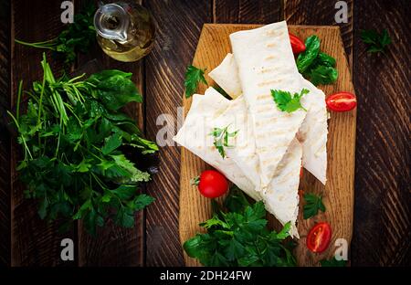 Gegrillte Tortilla Wraps mit Huhn und frischem Gemüse auf Holzbrett. Hühnerburrito. Mexikanisches Essen. Gesunde Ernährung Konzept. Mexikanische Küche.Top vie Stockfoto