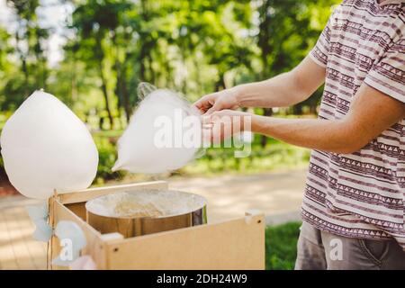 Thema ist eine Familie kleines Unternehmen Kochen Süßigkeiten. Hände close-up EIN junger männlicher Ladenbesitzer hält einen Kaufmann macht Zuckerwatte, fa Stockfoto