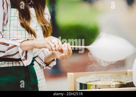 Thema ist eine Familie kleines Unternehmen Kochen Süßigkeiten. Hände close-up Junge Frau Händler Besitzer des Outlet macht eine Zuckerwatte, fair Stockfoto