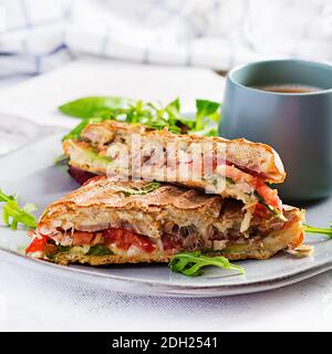 Gegrillte Club Sandwich Panini mit Rindfleisch, Tomaten, Käse, Salat und einer Tasse Kaffee. Leckeres Frühstück oder Snack. Stockfoto