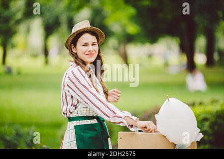 Foto Thema kleine Unternehmen Kochen Süßigkeiten. Eine junge kaukasische Frau mit einem Schürzenhändler im Hut macht der Besitzer des Outlet Stockfoto