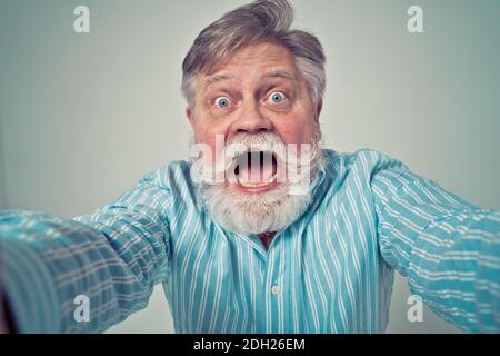 Lustige ältere Mann posiert in einem Fotoshooting. Happy Hipster macht lustige Ausdrücke. Konzept über Menschen und Lifestyle. Stockfoto