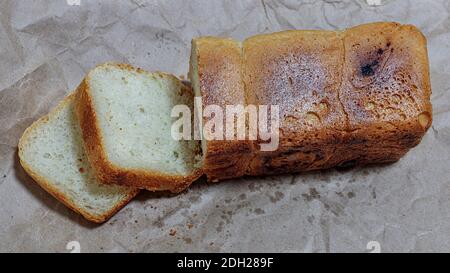Nahaufnahme von frisch gebackenem, teilweise geschnittenem Brot auf einem Blatt Kraftpapier. Selektives Fokusfoto von teilweise geschnittenem Brot. Stockfoto