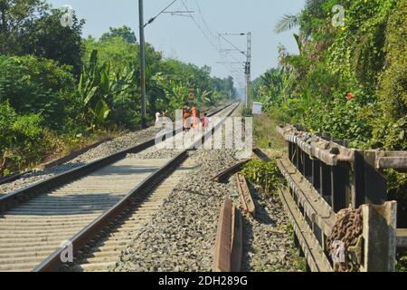 Nahaufnahme der Eisenbahnlinien und der elektrischen Oberleitung der Indian Railways, die durch die Landschaft fahren, selektive Fokussierung Stockfoto