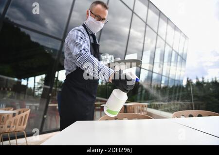 Kellner Reinigung der Tabelle mit Desinfektionsmittel Spray in einem Restaurant Stockfoto