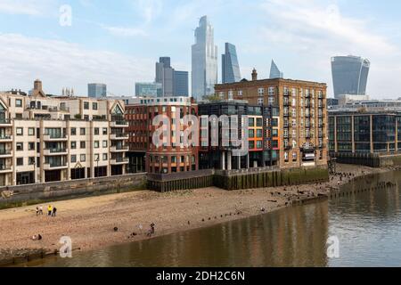 Blick auf das Ufer der Themse bei Ebbe mit Wohnhäusern und Wolkenkratzern im Hintergrund, Millennium Bridge, London Stockfoto