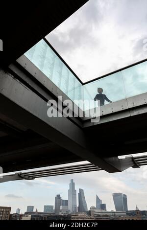 Low-Angle-Ansicht eines Kindes spielt auf der Millennium Bridge mit Stadtbild im Hintergrund, London Stockfoto