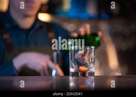 Der Barkeeper bereitet einen traditionellen altmodischen Cocktail mit Whiskey und Orange zu Stockfoto