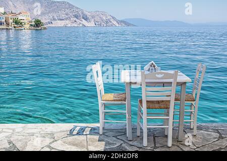 Stühle mit Tischen in typisch griechischer Taverne am Meer In Symi Stadt Stockfoto