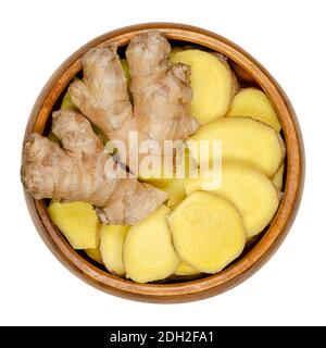 Frische Ingwerwurzeln, ganz und in Scheiben geschnitten, in einer Holzschale. Rhizome von Zingiber officinale, als duftendes Gewürz und als Volksmedizin verwendet. Stockfoto