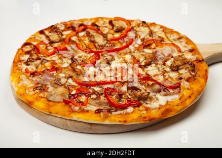 Köstliche Pizza mit Speck und Huhn Teriyaki auf einem Holzteller serviert, Zutaten Signature Sauce, Mozzarella Käse, Teriyaki Huhn, Speck, bulgarischer Pfeffer, Teriyaki Sauce auf weiß Stockfoto