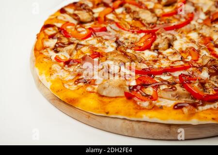 Köstliche Pizza mit Speck und Huhn Teriyaki auf einem Holzteller serviert, Zutaten Signature Sauce, Mozzarella Käse, Teriyaki Huhn, Speck, bulgarischer Pfeffer, Teriyaki Sauce auf weiß Stockfoto