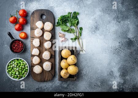 Meeresdelikatessen, Jakobsmuscheln mit Kartoffeln, grüne Erbsenblüten und Minze, Draufsicht, auf grauem Hintergrund mit Kopierraum Stockfoto