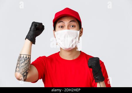 Covid-19, Online-Shopping in Quarantäne, Lieferkonzept. Nahaufnahme des glücklichen Chanting Kurier in roter Mütze und T-Shirt, tragen med Stockfoto