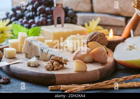 Käseplatte aus verschiedenen Käsesorten - Emmentaler, hausgemachte, Parmesan, Blauschimmelkäse, Brotscheiben, Walnüsse, Rosinen, Birne, Gra Stockfoto