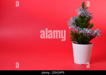 Kleine Weihnachtsbaumschmuck auf rot. Zweige eines Weihnachtsbaums. Konzept für Weihnachten oder Neujahr Shopping Stockfoto