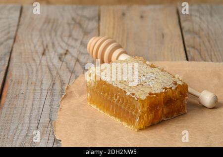 Honig in Waben und Löffel auf Geschenkpapier auf einem Holztisch. Selektiver Fokus. Stockfoto