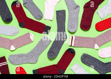 Oben mit vielen Socken unterschiedlicher Textur, Farbe und Form auf grünem Hintergrund. Flache Laie mit Wintersocken. Stockfoto