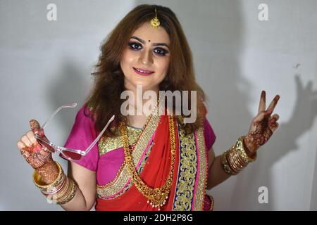 indische Braut in traditioneller Kleidung und Sonnenbrille in der Hand Stockfoto