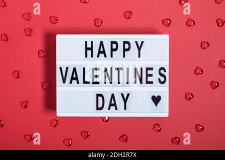 Lightbox mit Wörtern für Happy Valentines Day Draufsicht auf rotem Hintergrund. Grußkarte zum Valentinstag. Stockfoto