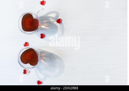 Zwei Teetassen in Herzform mit roten Herzen auf weißem Holztisch Draufsicht. Konzept zum Valentinstag. Romantisches Abendessen am Valentinstag. Stockfoto