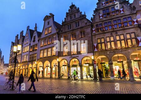 Münster, NRW, 09. Dezember 2020. Nur wenige wagen sich während der sogenannten "Lock down light"-Maßnahmen in Deutschland auf den normalerweise sehr belebten Prinzipalmarkt zum Shoppen. Festliche Lichter erleuchten das historische Stadtzentrum von Münster, das kulturelle Zentrum Westfaliens, entlang dem Rathaus und dem Prinzipalmarkt mit seinen berühmten gotischen Fassaden. Die malerische Stadt, ein mittelalterliches Mitglied der Hanse, war der Geburtsort der westfälischen Diplomatie. Stockfoto