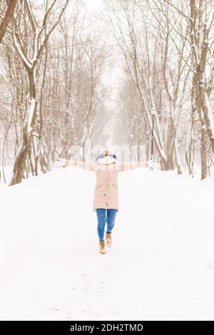 Junges Mädchen in einem verschneiten Wald im Winter. Porträt eines Mädchens in einem Winterpark mit Schnee. Eine Frau geht Schneeflocken fangen Stockfoto