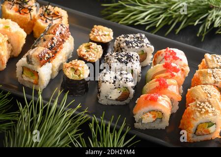 Weihnachtliches Sushi-Set mit Weihnachtsdekoration. Nahaufnahme. Weihnachtsfeier oder Neujahrsparty. Stockfoto
