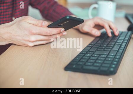 Home-Office-Konzept: Mann tippt auf seinem schwarzen Handy Stockfoto