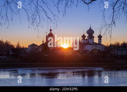 Tichwin Himmelfahrtskloster. Abenduntergang, die Sonne scheint zwischen den Kirchen des Klosters, eine schöne Landschaft. Tichwin Stockfoto