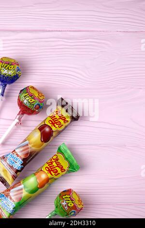 CHARKOW, UKRAINE - 24. NOVEMBER 2020: Chupa Chups Produkte auf pastellrosa Holztisch. Chupa Chups ist eine spanische Marke von Lollipop und anderen confectio Stockfoto