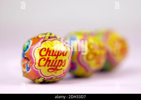 CHARKOW, UKRAINE - 24. NOVEMBER 2020: Chupa Chups Produkte auf pastellrosa Holztisch. Chupa Chups ist eine spanische Marke von Lollipop und anderen confectio Stockfoto