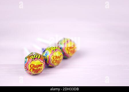 CHARKOW, UKRAINE - 24. NOVEMBER 2020: Chupa Chups Produkte auf pastellrosa Holztisch. Chupa Chups ist eine spanische Marke von Lollipop und anderen confectio Stockfoto