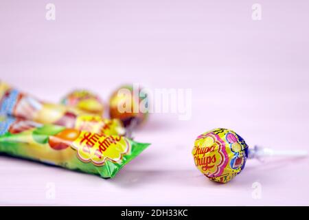 CHARKOW, UKRAINE - 24. NOVEMBER 2020: Chupa Chups Produkte auf pastellrosa Holztisch. Chupa Chups ist eine spanische Marke von Lollipop und anderen confectio Stockfoto