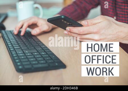 Home Office-Konzept: Mann tippt auf seinem schwarzen Handy, Text Home Office Arbeit Stockfoto